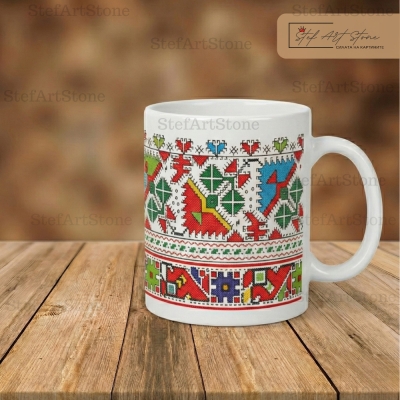 Керамична чаша с многоцветна българска шевица върху дървена маса